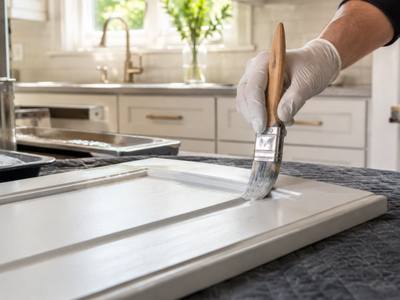 A brush cutting in white paint along the edge of a cabinet door.